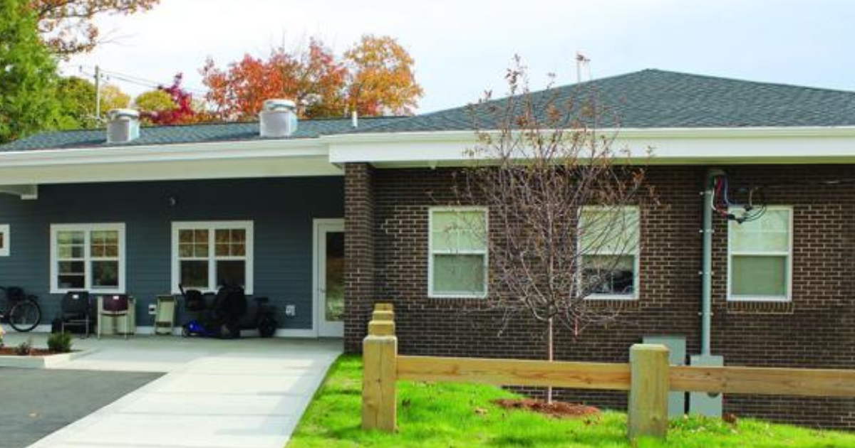 Exterior of Project HOPE in Willimantic, with a paved entrance walkway and an orange motorcycle parked in front.